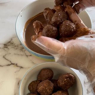 Una persona tiene in mano una ciotola di polpette ricoperte di cioccolato.