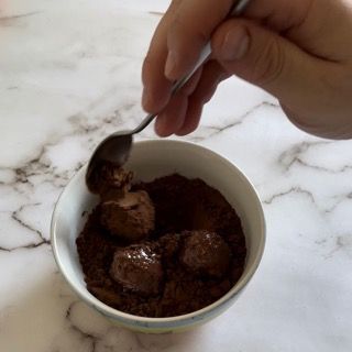 Una persona sta immergendo un cucchiaio in una ciotola di gelato al cioccolato