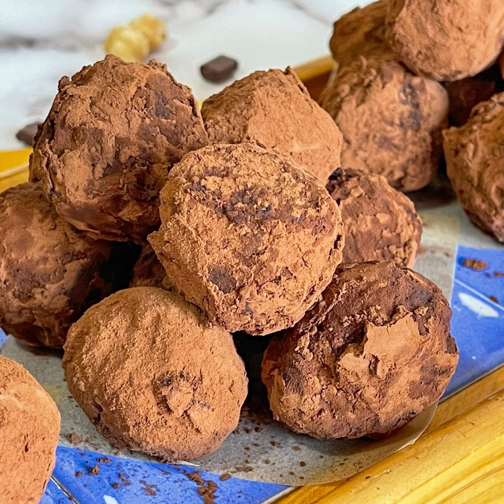 Una pila di tartufi al cioccolato ricoperti di cacao in polvere su un piatto blu.