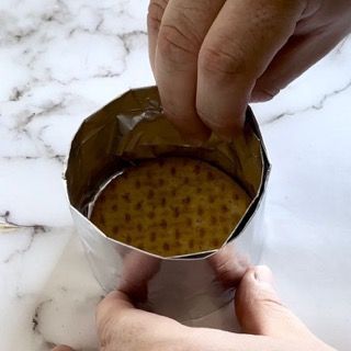 Una persona sta mettendo un cracker in un contenitore di carta stagnola.