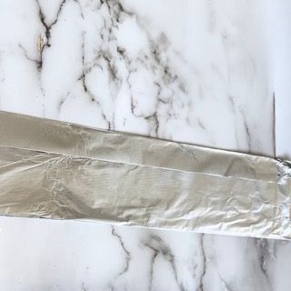 Un pezzo di foglio di alluminio è appoggiato su una superficie di marmo.