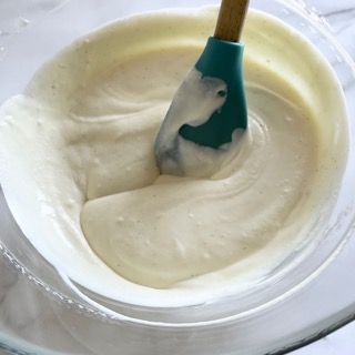 Una ciotola di besciamella con una spatola blu dentro.