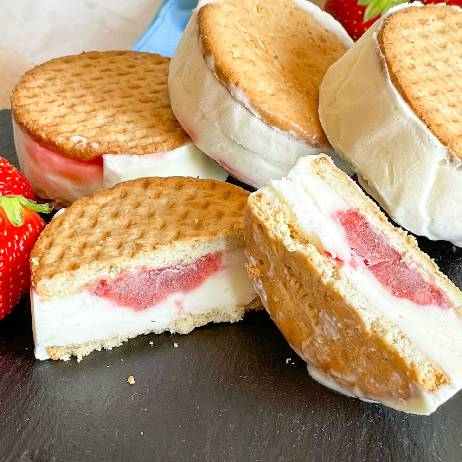 Diversi sandwich al gelato con fragole sullo sfondo