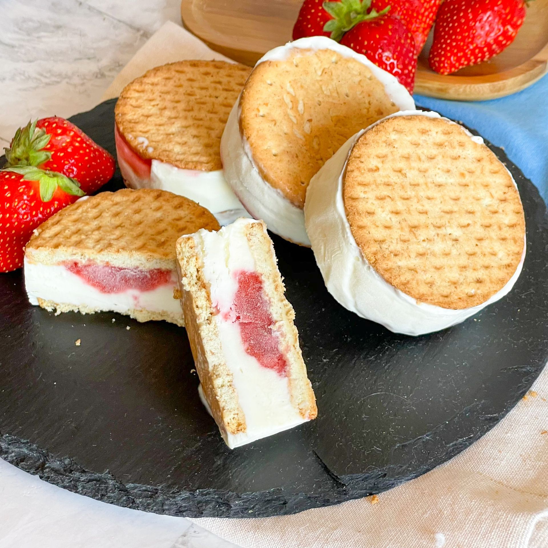 Un piatto nero guarnito con sandwich di gelato e fragole