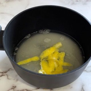 Una pentola nera piena di liquido e pezzi di cibo gialli