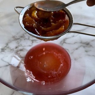 Si usa un colino per filtrare un pomodoro in una ciotola