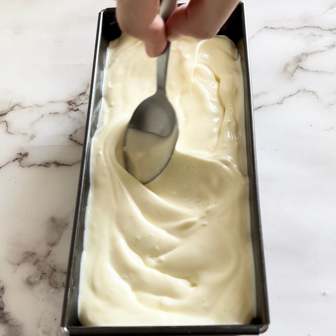 Una persona tiene un cucchiaio sopra una pagnotta di gelato