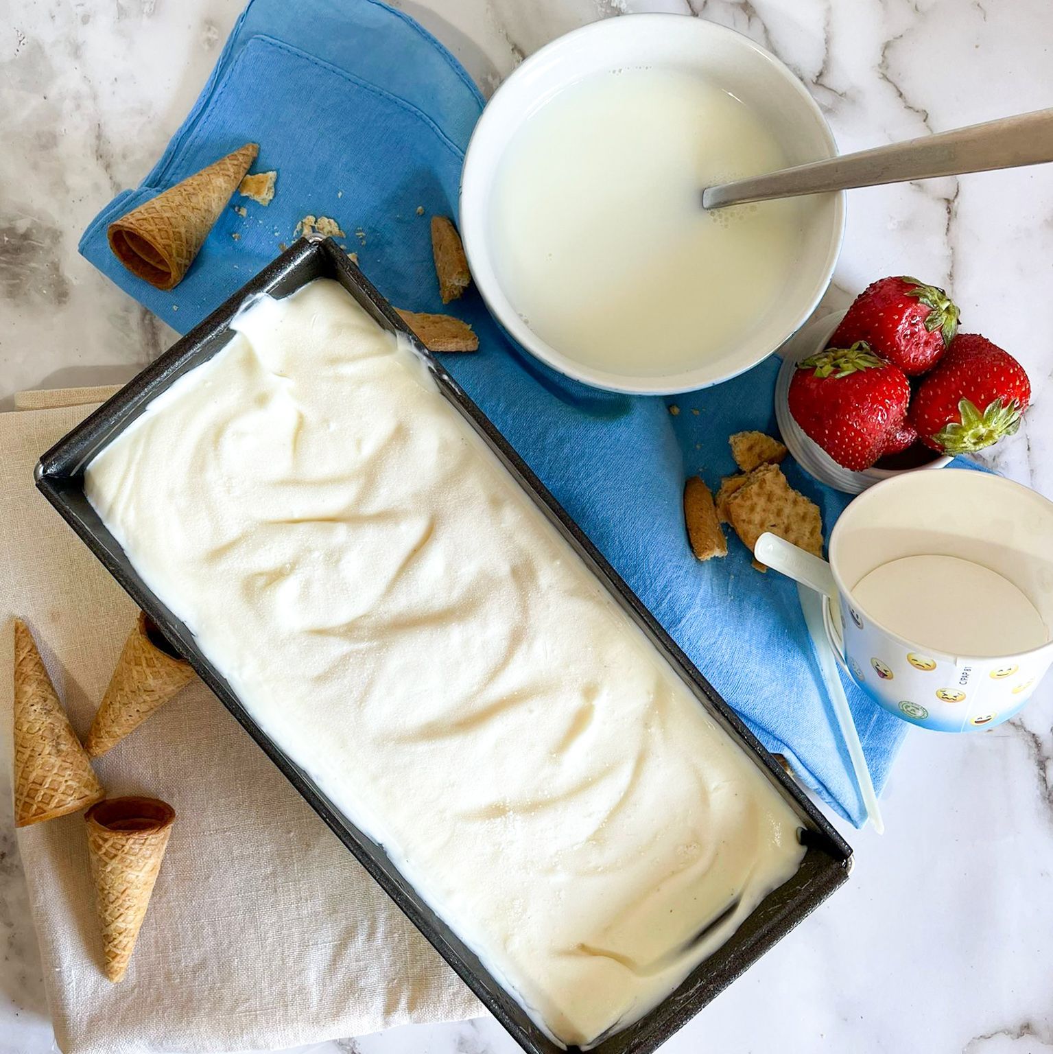 Una vaschetta di gelato accanto a una ciotola di latte e fragole.