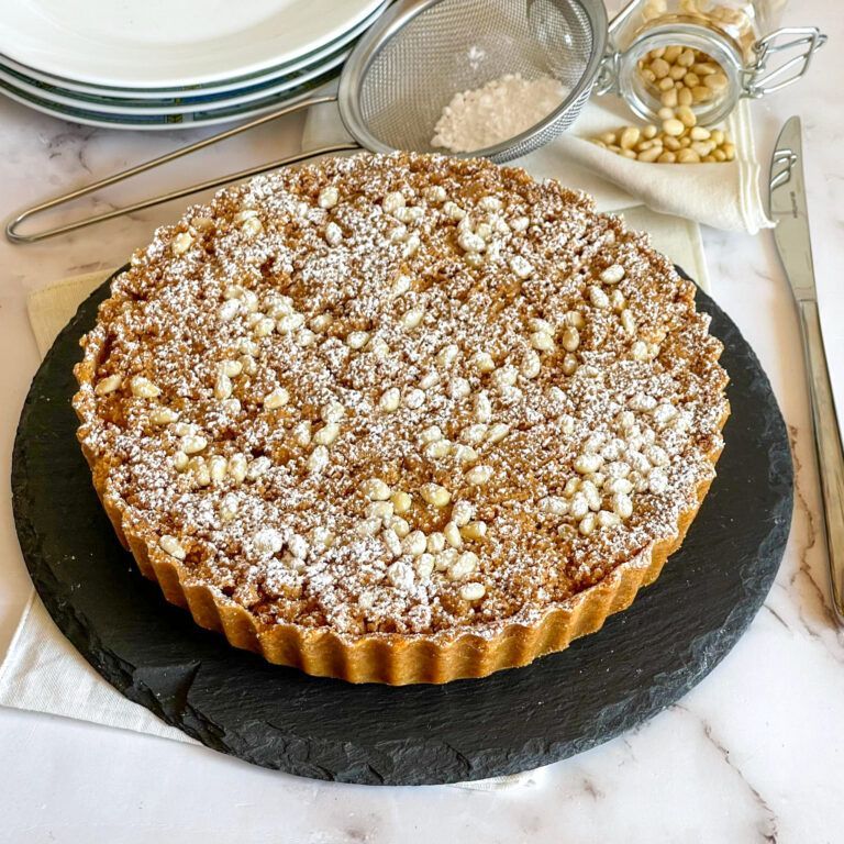 Una torta ricoperta di zucchero a velo è appoggiata su un piatto nero su un tavolo.