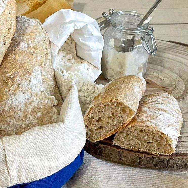 Un cestino di pane è appoggiato su un tavolo di legno accanto a un barattolo di burro.