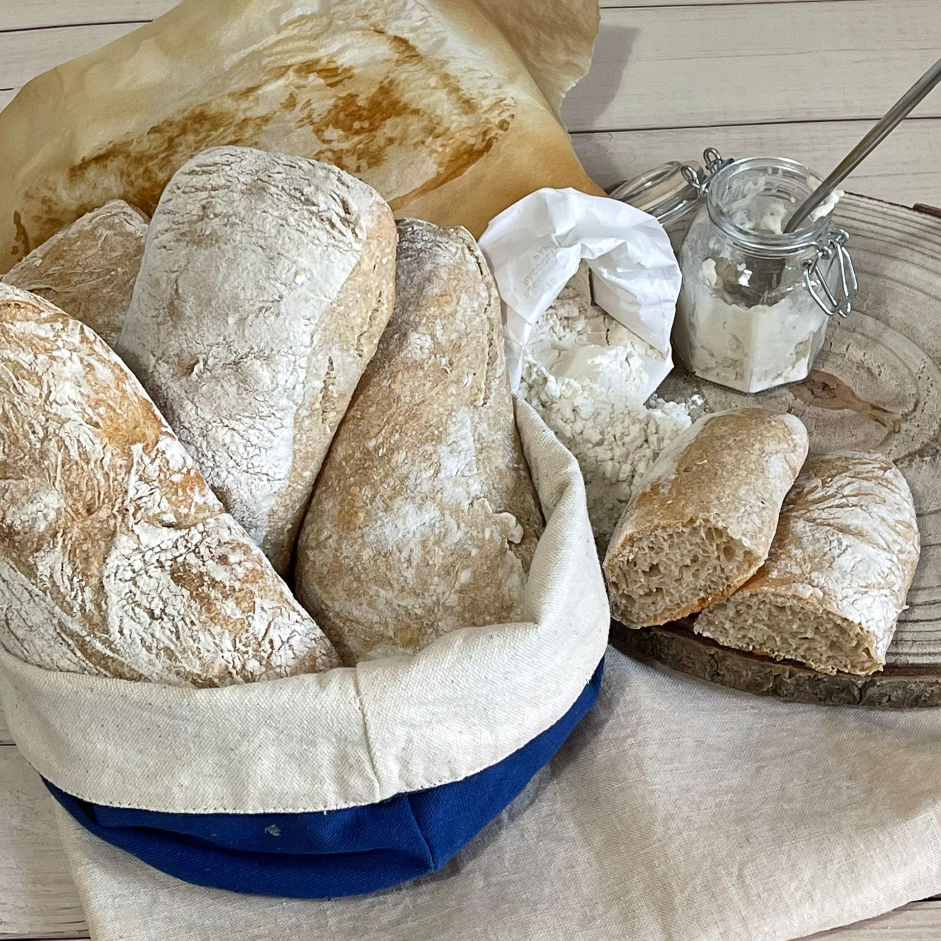 Un cestino pieno di pane e un barattolo di burro su un tavolo.