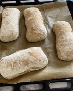 Quattro pagnotte di pane sono adagiate su una teglia.