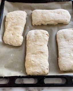 Quattro pagnotte di pasta sono adagiate su una teglia da forno