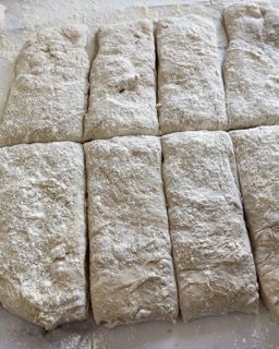Un pezzo di pasta viene tagliato a quadrati su un tavolo.