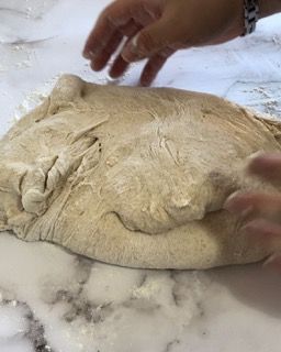 Una persona sta impastando un pezzo di pasta su un tavolo.