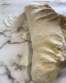 Un pezzo di pasta è appoggiato su un bancone di marmo.