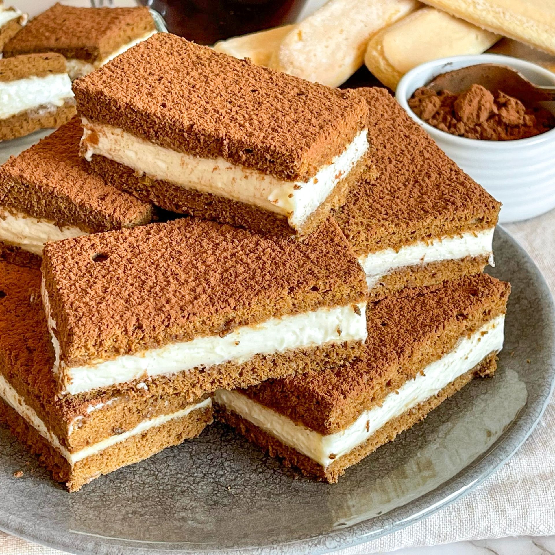 Un piatto di panini al tiramisù impilati uno sopra l'altro su un tavolo.