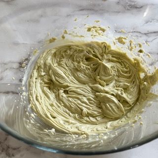 Una ciotola di glassa verde è appoggiata su un tavolo.