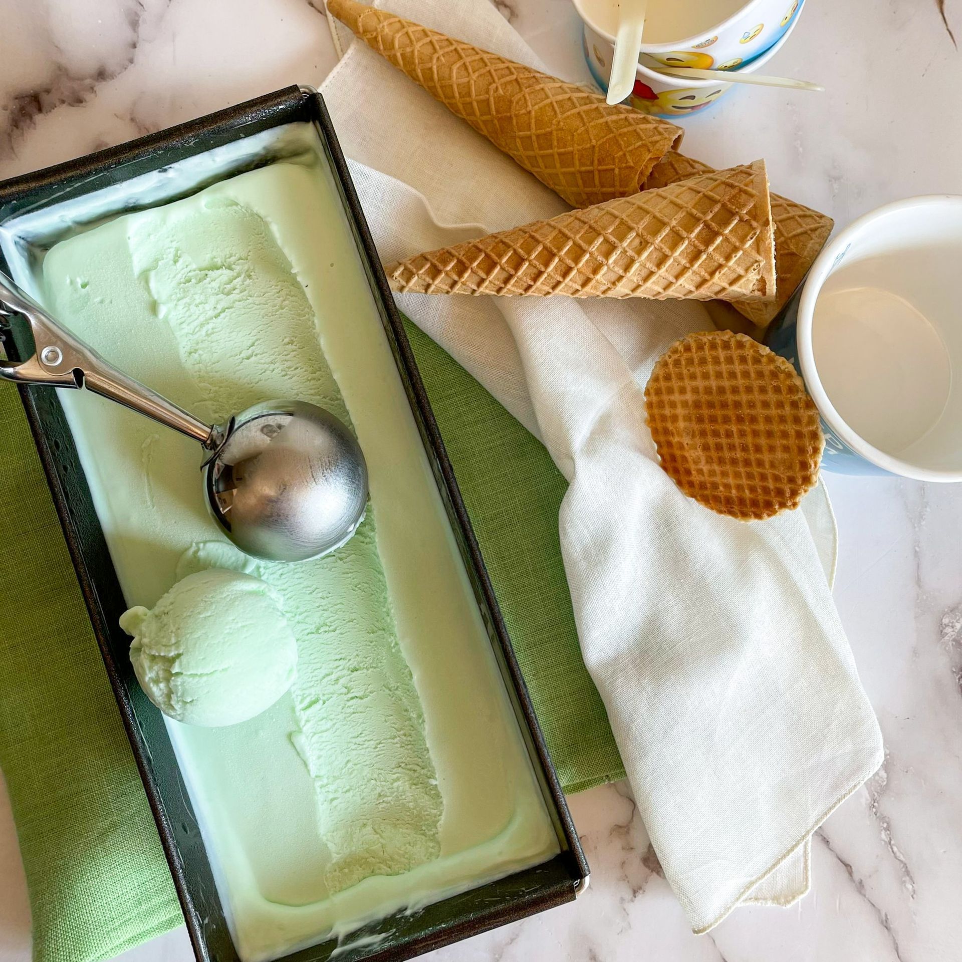 Una scatola di gelato con una pallina e dei coni su un tavolo.