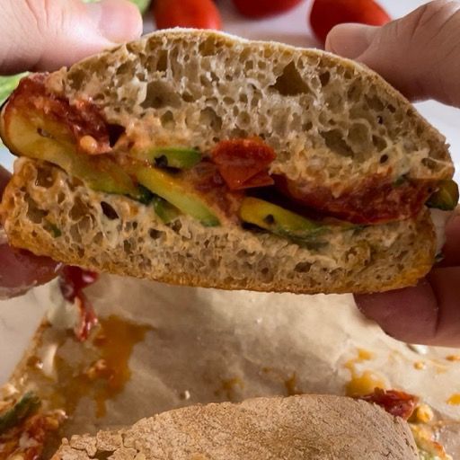 Una persona tiene in mano un panino mezzo mangiato