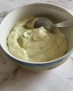 Una ciotola di salsa ranch con un cucchiaio dentro.