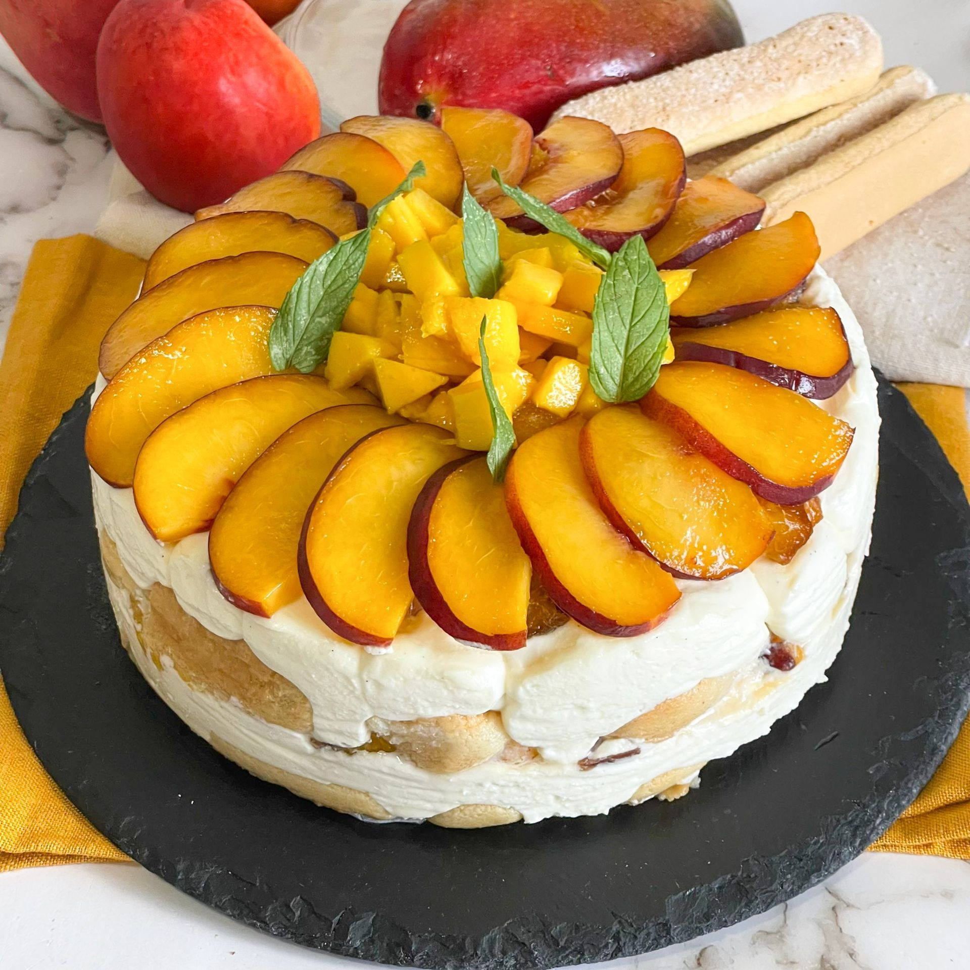 Una torta con sopra fette di pesche e mango