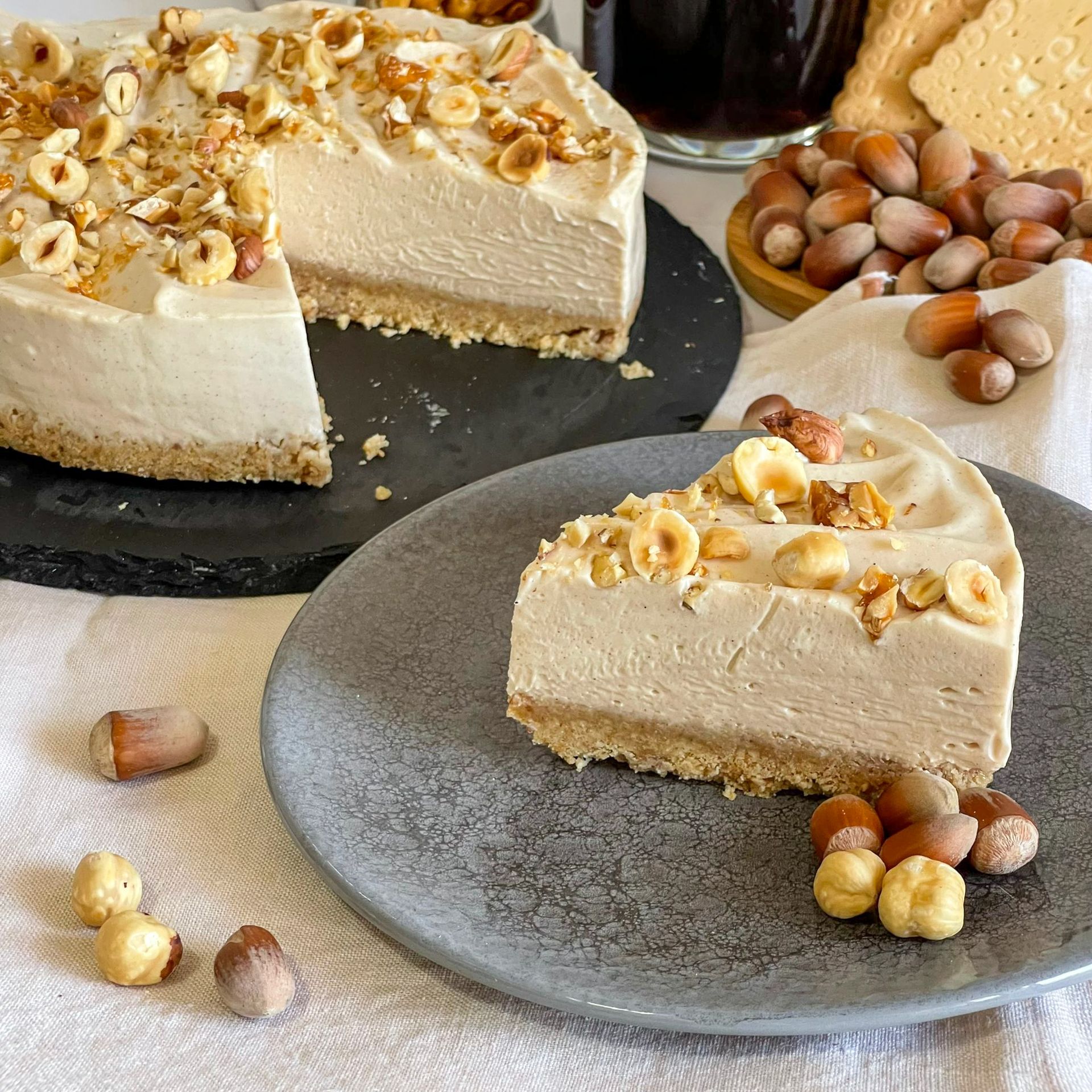 Una fetta di torta su un piatto accanto a una torta su un tavolo.