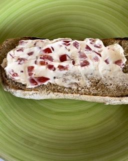 Un panino con formaggio cremoso e pomodori su un piatto verde.