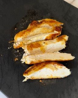 Petti di pollo affettati su un tagliere nero