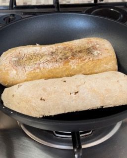 Due pagnotte di pane stanno cuocendo in una padella