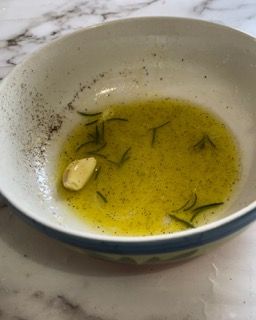 Una ciotola di salsa con aglio e rosmarino su un tavolo.