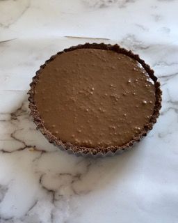 Una crostata al cioccolato è appoggiata su una superficie di marmo.
