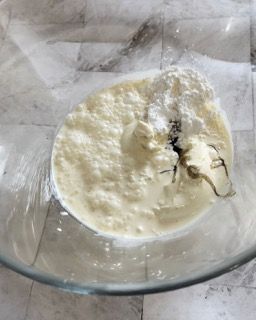 Una ciotola di vetro piena di un liquido bianco e zucchero a velo.
