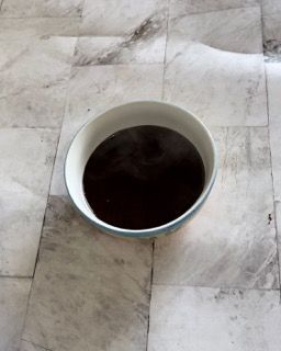 Una ciotola di liquido marrone su un pavimento piastrellato