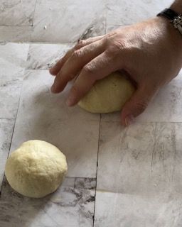 Una persona sta impastando una palla di pasta su un pavimento piastrellato.
