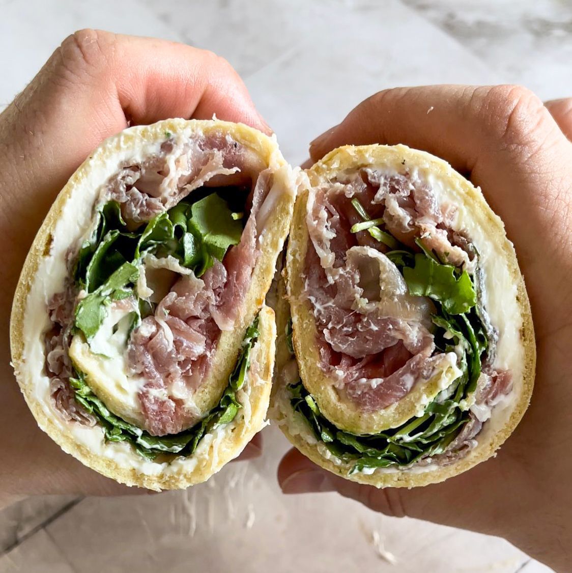 Una persona tiene in mano un panino tagliato a metà