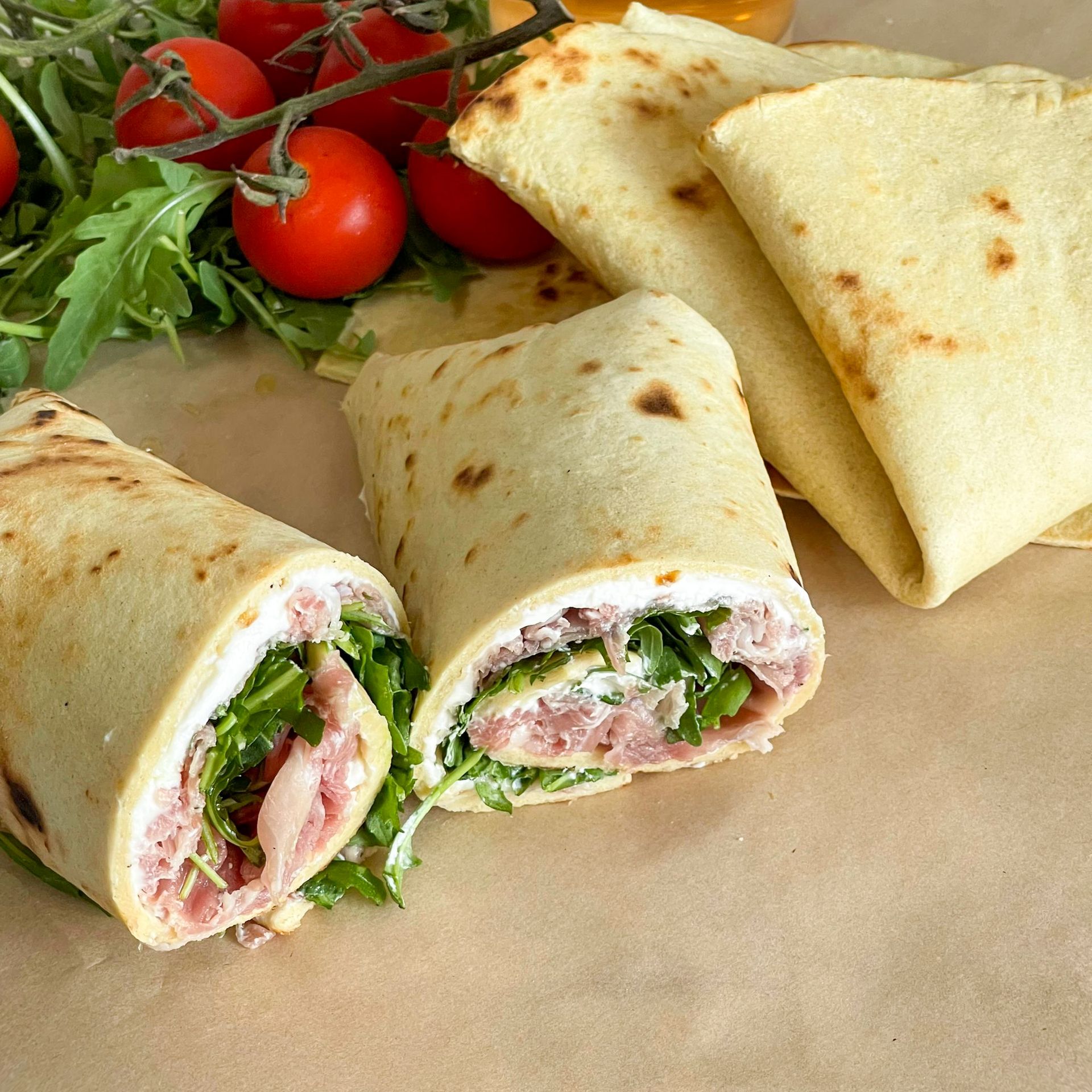 Un primo piano di una tortilla wrap su un tavolo con pomodori sullo sfondo