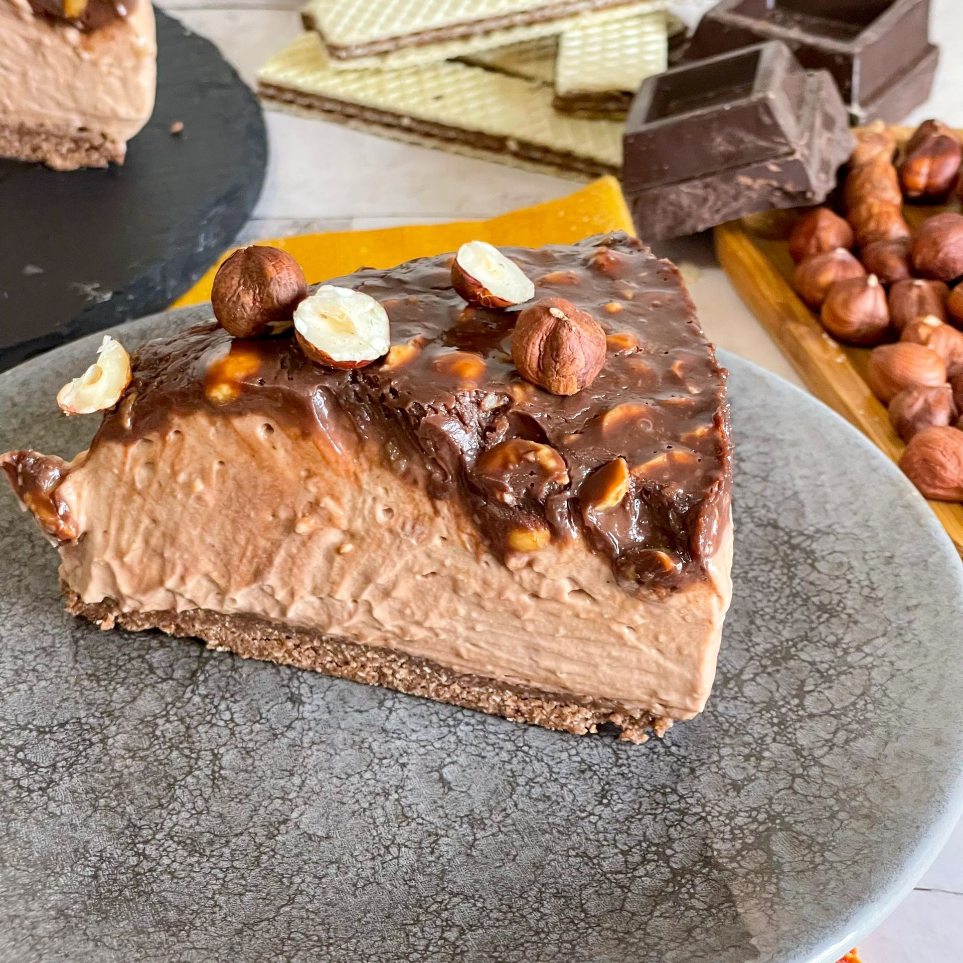 Una fetta di cheesecake al cioccolato con sopra delle noci è su un piatto.