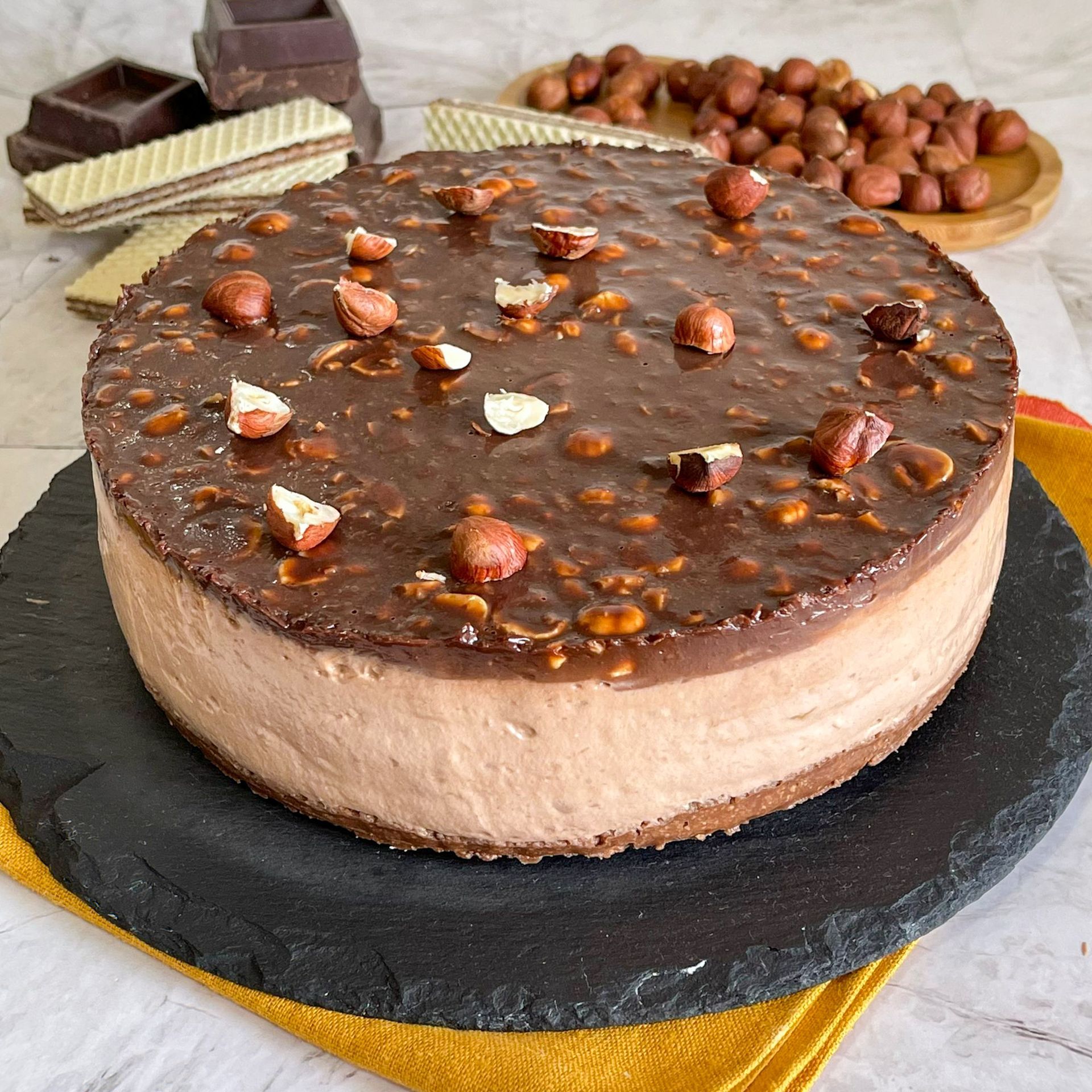 Una torta al cioccolato con sopra delle noci è appoggiata su un piatto nero.