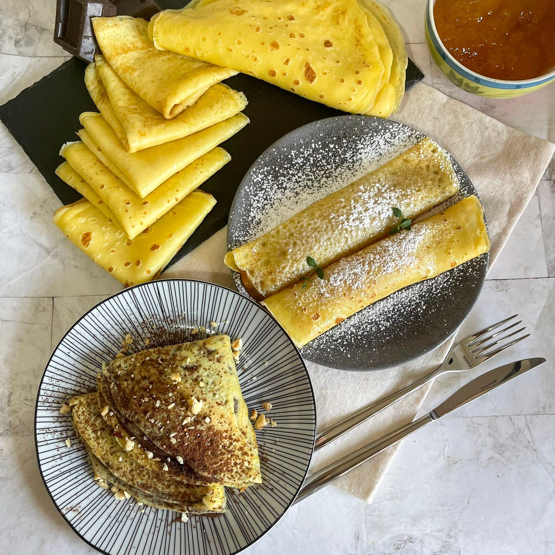 Un tavolo sormontato da piatti di cibo e una tazza di marmellata.