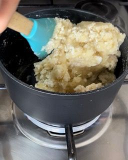 Una persona sta mescolando una pentola di cibo con una spatola blu
