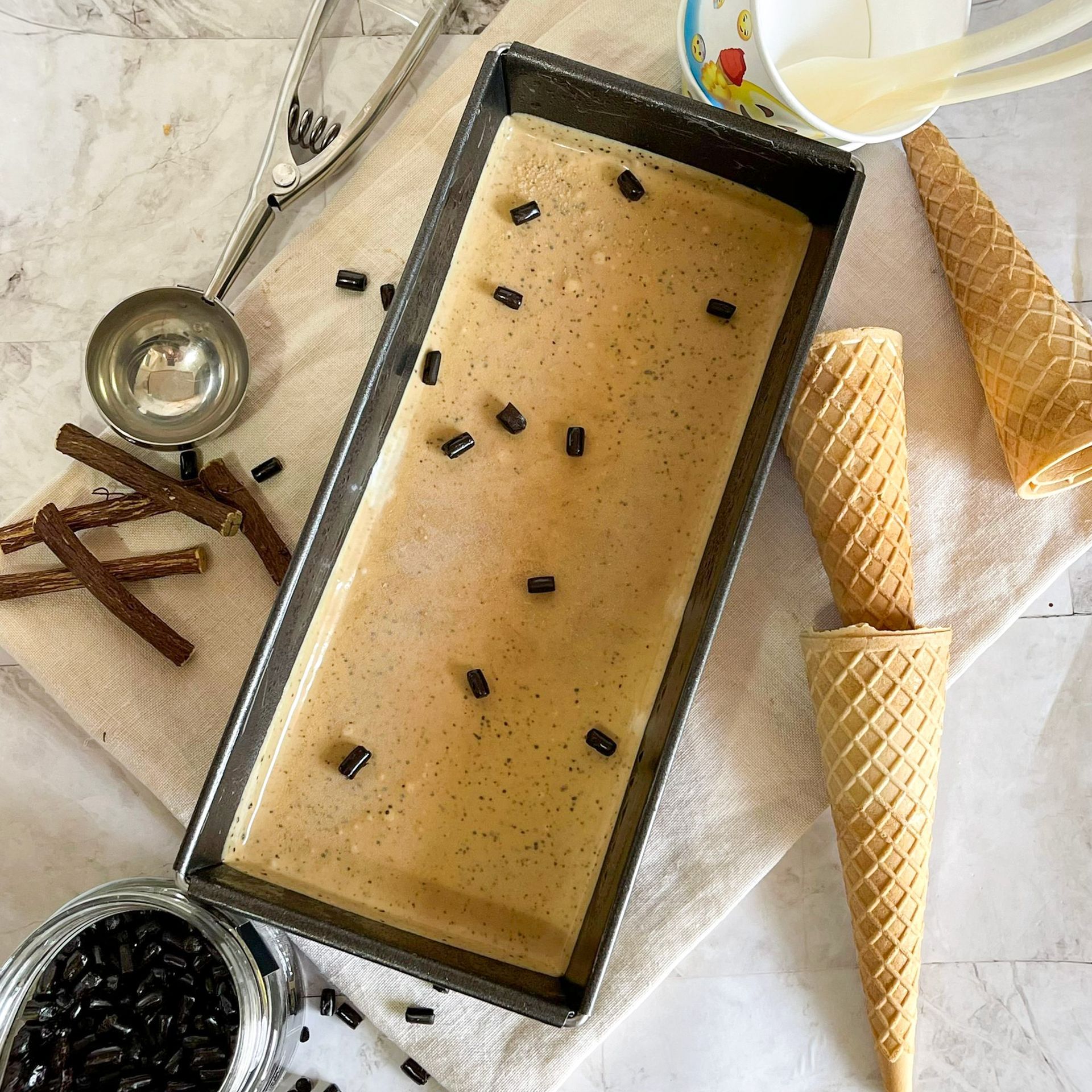 Una vaschetta di gelato è appoggiata su un tavolo accanto ai coni gelato.