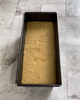 Uno stampo per plumcake pieno di impasto è appoggiato su un tavolo.