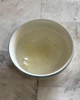 Una ciotola bianca piena d'acqua è appoggiata su un pavimento piastrellato.