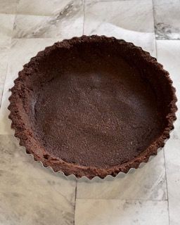 Una crosta di torta al cioccolato è appoggiata su un pavimento piastrellato