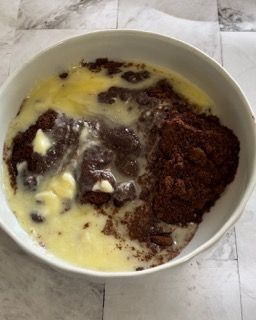 Una ciotola bianca piena di un composto di cioccolato e burro