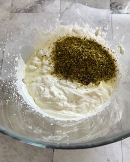 Una ciotola di vetro piena di panna montata e polvere verde.