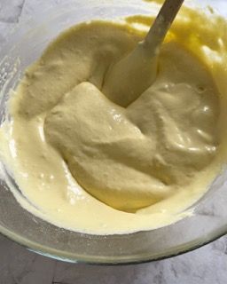 Una ciotola di salsa gialla con un cucchiaio dentro.