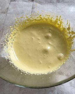 Una ciotola piena di liquido giallo è appoggiata su un tavolo.