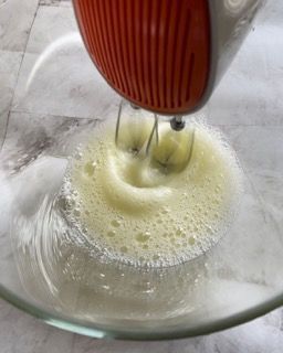 Un mixer mescola le uova in una ciotola di vetro.